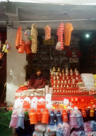 A man sits in a stall surround by plastic containers of different colours.