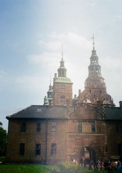 The spires of Rosenborg Palance rise above the brick building that once housed the King of Denmark. Visitors enter through a gate at the bottom of the photo.