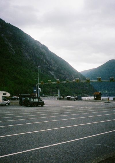 A car waits in a numbered line in an otherwise empty parking lot. They are waiting in a cark park by the water for the incoming ferry.