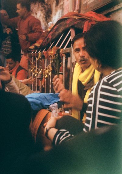 A priest gives instructions to a female worshipper seated on the floor.