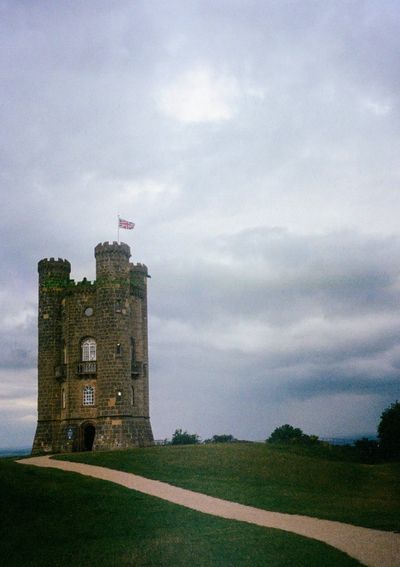 A lone tower stands in a field with grey skies. The Union Jack flag flies atop it.