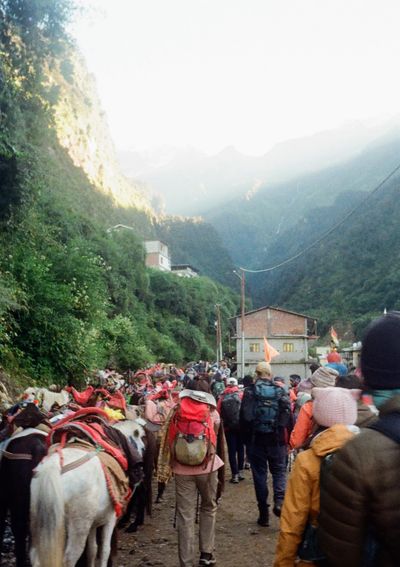 People and horses jostle for position on a dirt road at the start of a hike. 