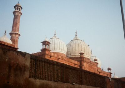 A mosque appears above an orange coloured wall.