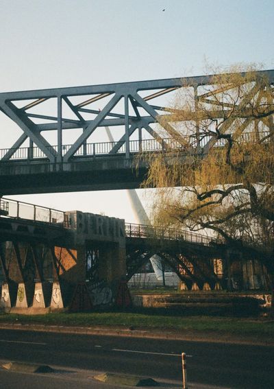 Stone characters spell out 'Berlin', beneath an overhead S-bahn railway bridge.