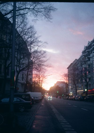 Looking down a street line with parked cars towards the setting sun.