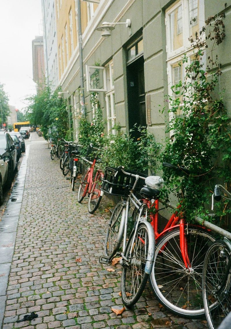 Bikes parked along a wall on a cobbled pavement.