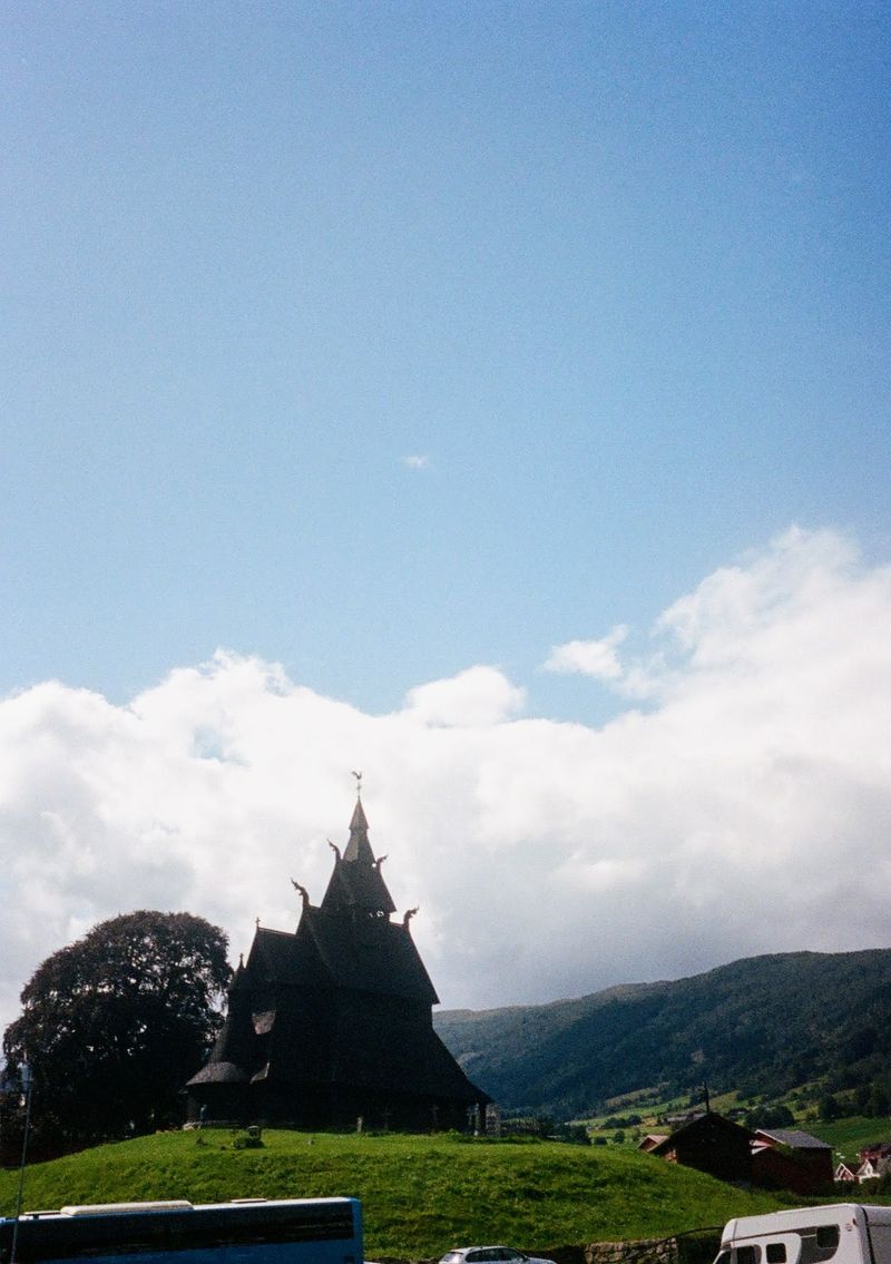 A stave church sits atop a green hill. 