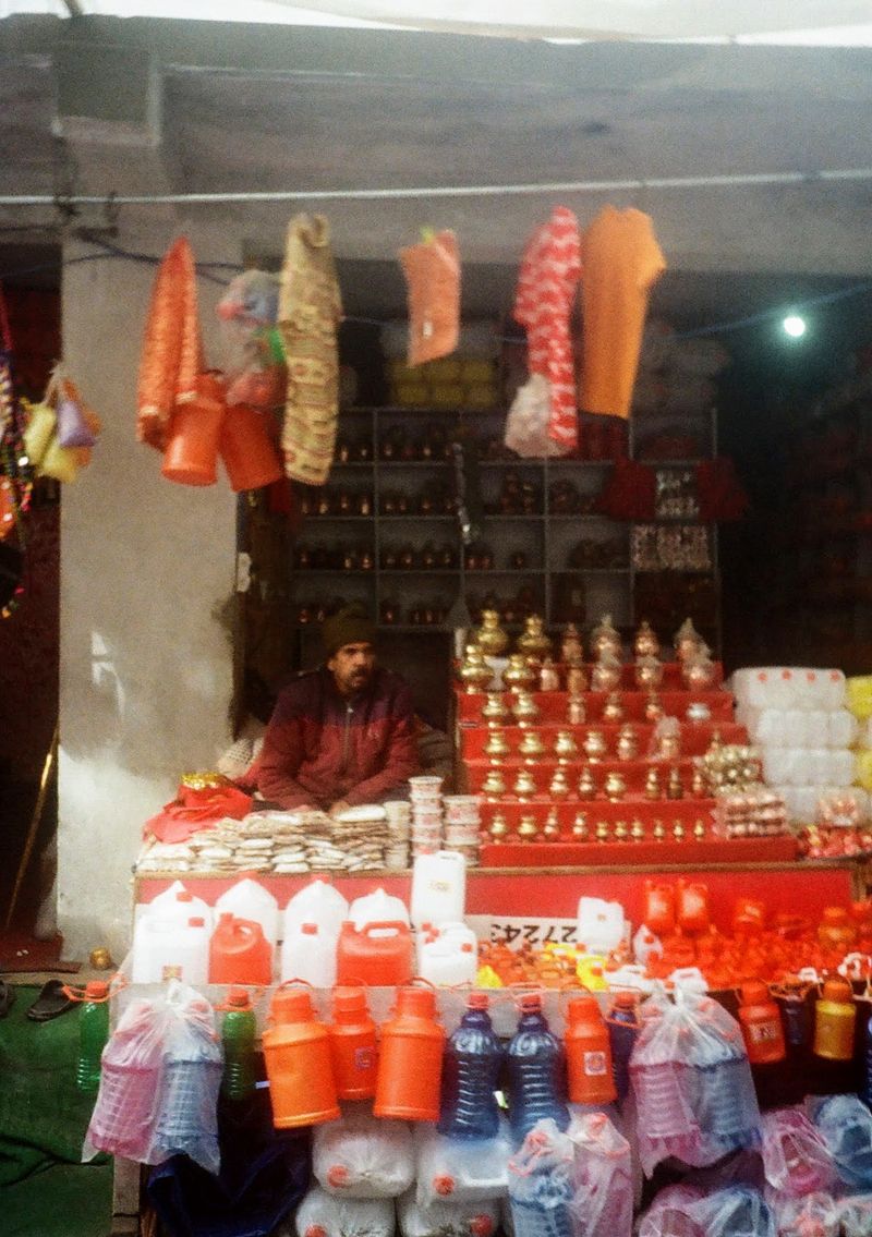 A man sits in a stall surround by plastic containers of different colours.