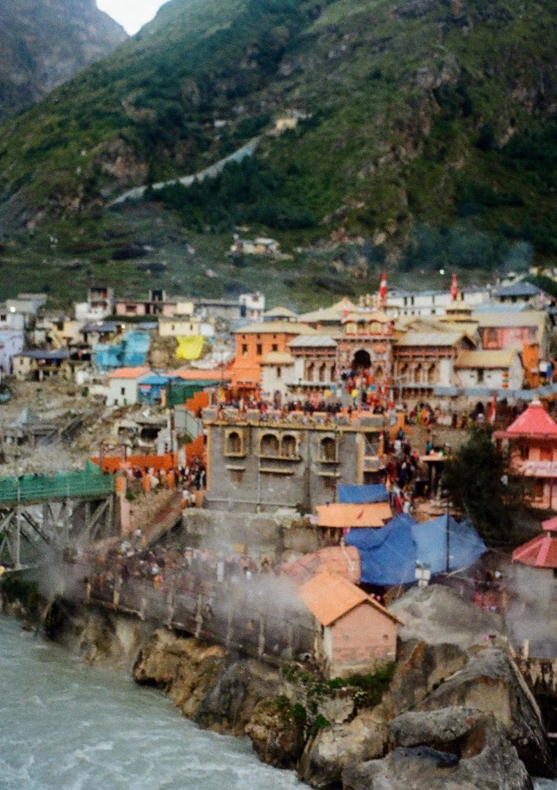 Hot baths line the banks of a flowing river, with a temple situated on the hill behind them.