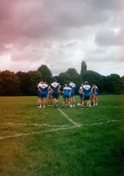 Players wearing blue and white Chinese Taipei shirts stand in a circle in the middle of a field.