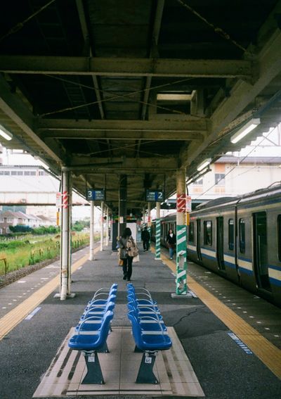 A woman walks aways from the camera having just got off the traing stopped at an otherwise empty platform.